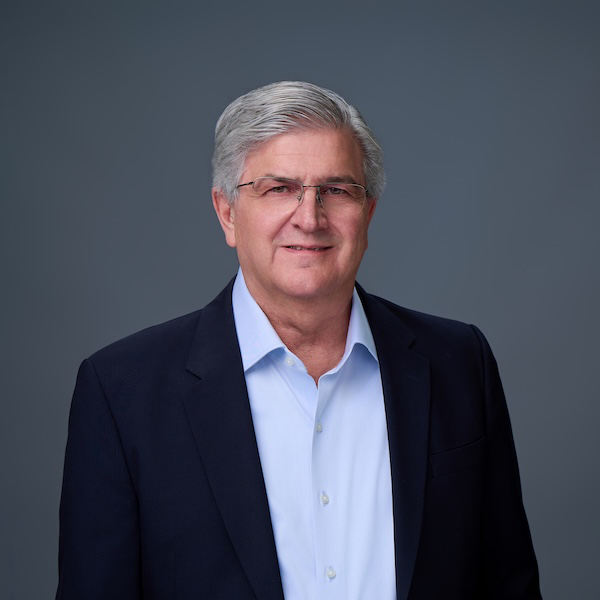 Joe Colonnetta, man with grey hair, glasses, wearing a shirt and blazer.