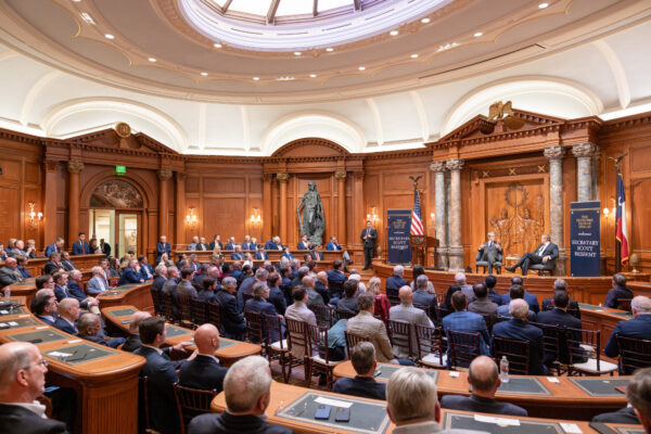 A seated group of event attendees listening to man speaking.